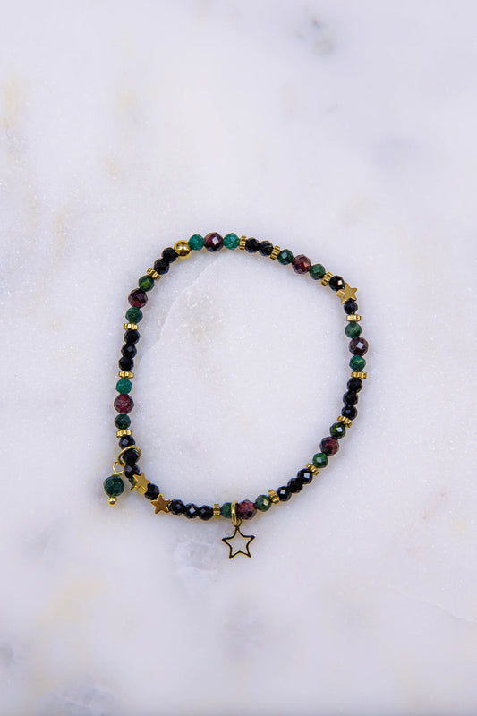 Zbliżenie (makro) na detale bransoletki: pozłacana zawieszka gwiazda oraz fasetowane kamienie naturalne – błyszczący czarny spinel i głęboki czerwony granat.