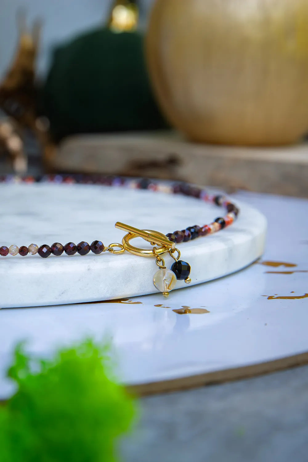 SERCE KRÓLOWEJ - NASZYJNIK Z GRANATU, SPINELU I CYTRYNU, elegancki naszyjnik z kolorowymi kamieniami, ułożony na białym tle z dekoracją w tle.