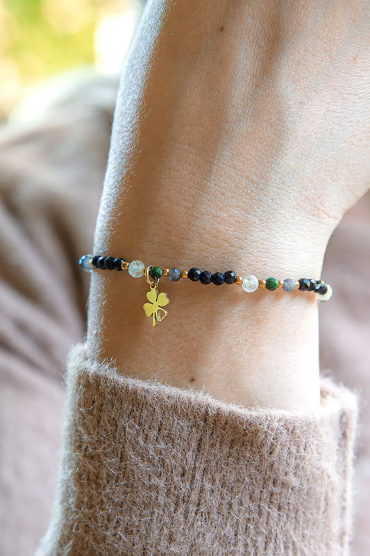 SZEPT SZMARAGDOWEJ WYSPY - BRANSOLETKA Z LEPIDOLITU, CYTRYNU I LABRADORYTU. Delikatna bransoletka z kamieni z pozłacaną koniczynką na tle beżowej, kobiecej bluzy.