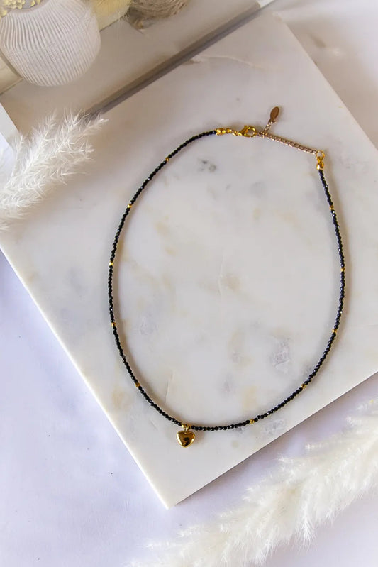 Złote Serduszko Naszyjnik Turmalin: czarny naszyjnik z kulkami z turmalinu, złotymi akcentami i delikatnym złotym serduszkiem.