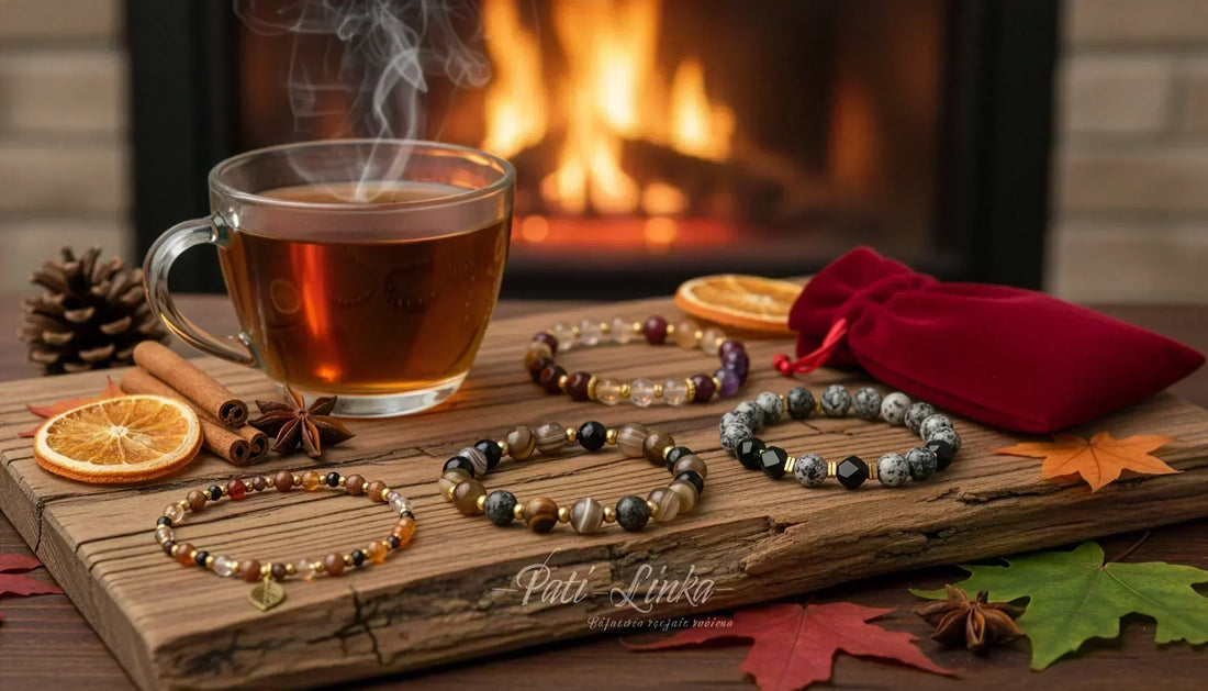 Jesienna, ciepła aranżacja prezentująca ręcznie robione bransoletki z kamieni naturalnych Pati Linka. Osobiste talizmany mocy leżą na drewnie obok parującej herbaty, w tle widać płomienie kominka.