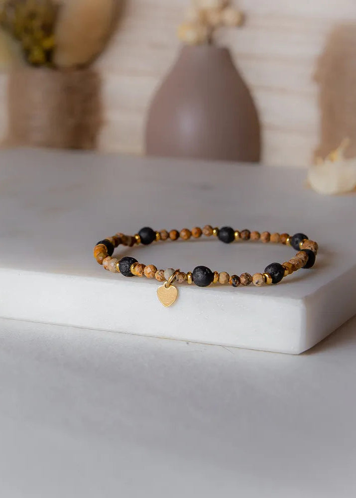 Cieple Serce Bransoletka W Odcieniach Ziemi Zlote Serce z kamieniami w ziemistych barwach i lawą, ozdobiona złotym serduszkiem.
