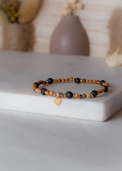 Cieple Serce Bransoletka W Odcieniach Ziemi Zlote Serce z kamieniami w ziemistych barwach i lawą, ozdobiona złotym serduszkiem.