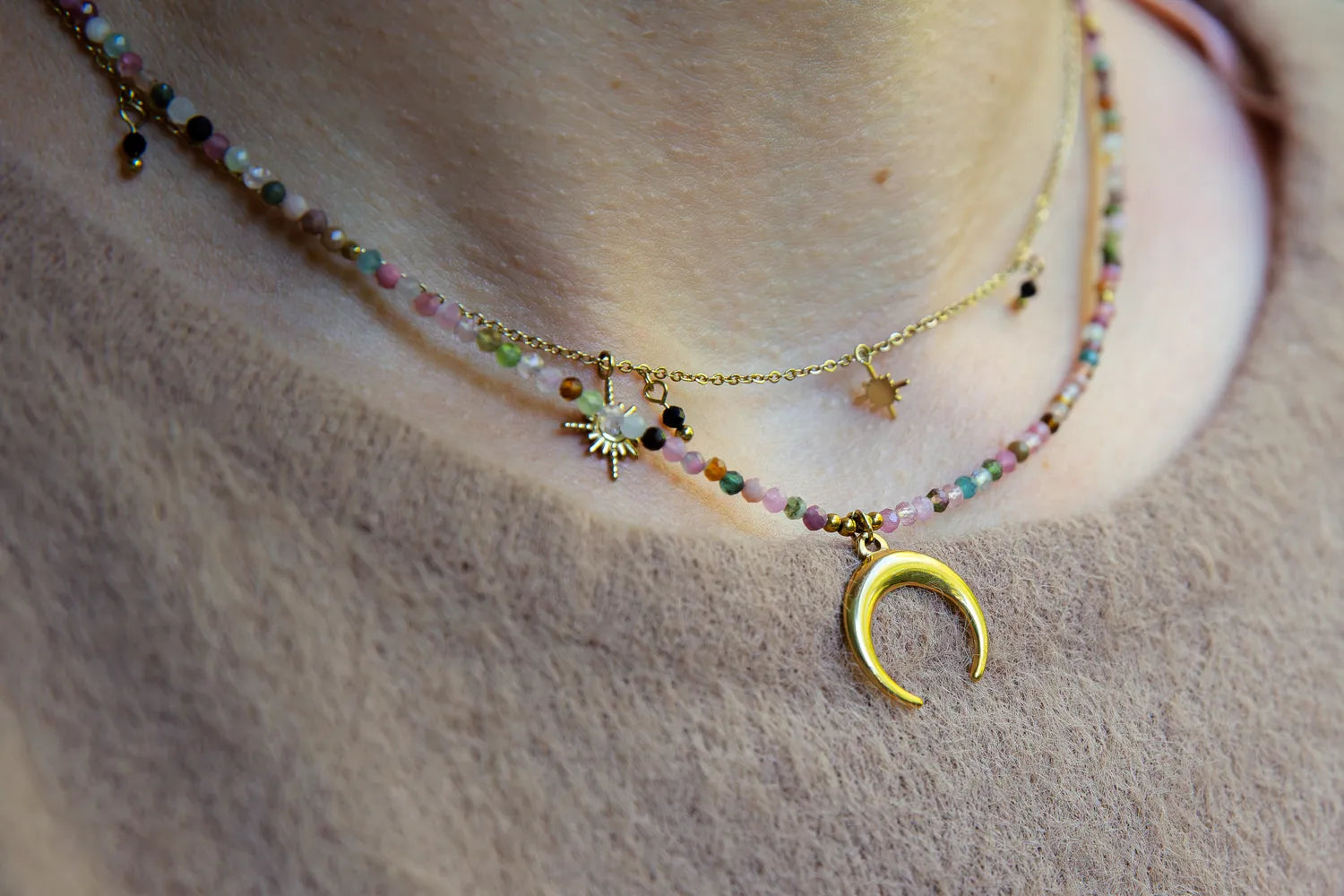 CZAR KSIĘŻYCA - NASZYJNIK Z KOLOROWEGO TURMALINU Z KSIĘŻYCEM. Naszyjnik z kolorowymi koralikami turmalinu i złotym księżycem, na tle skóry.