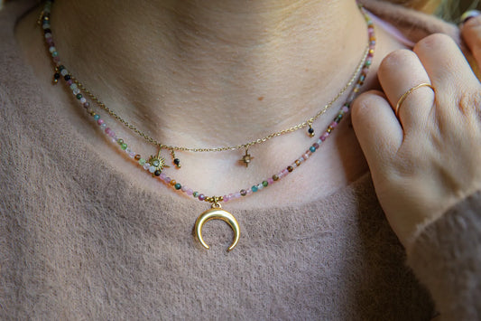 CZAR KSIĘŻYCA - NASZYJNIK Z KOLOROWEGO TURMALINU Z KSIĘŻYCEM. Złoty naszyjnik z księżycowym wiszącym elementem i kolorowymi koralikami turmalinu, na tle delikatnej, beżowej bluzki.