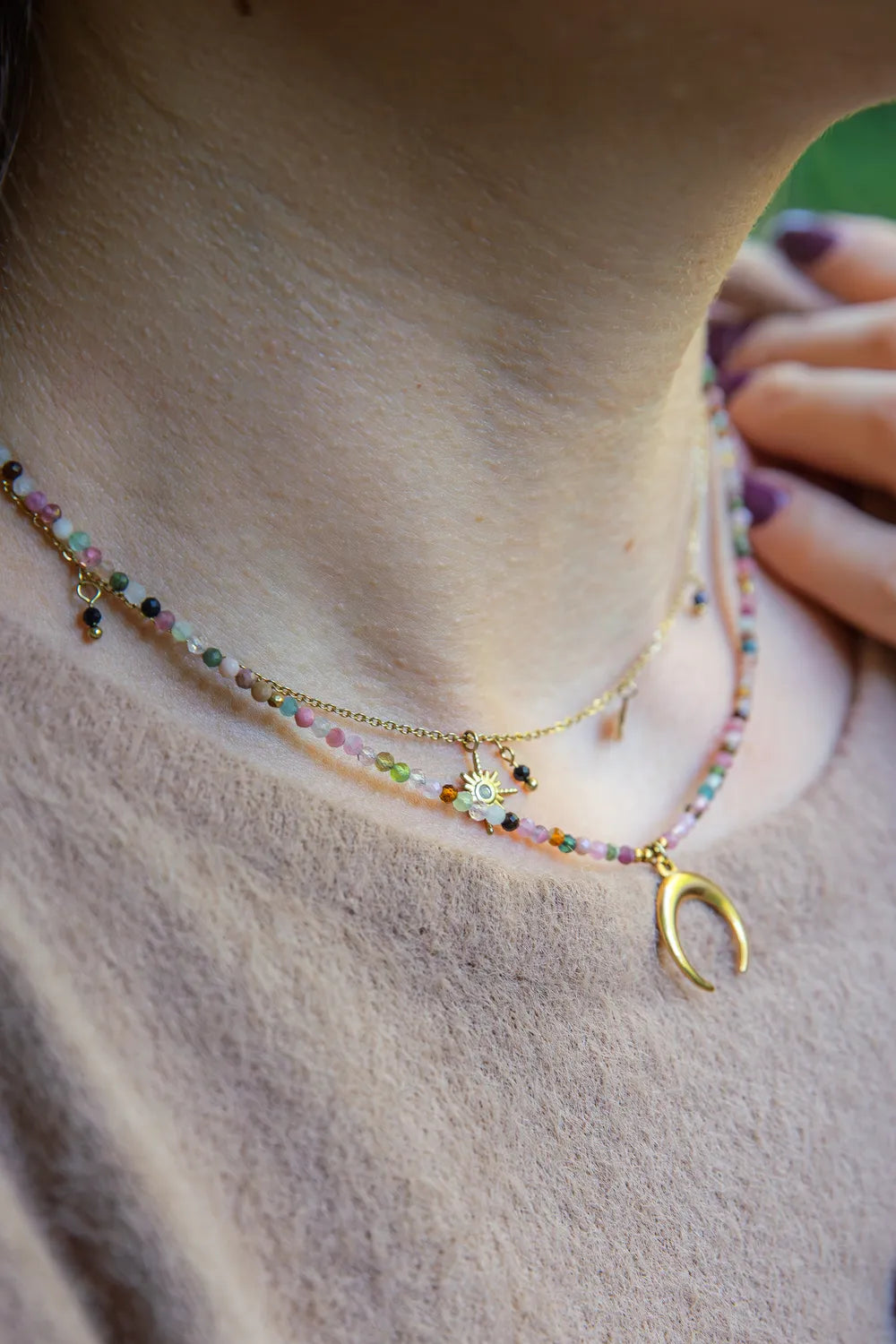 CZAR KSIĘŻYCA - NASZYJNIK Z KOLOROWEGO TURMALINU Z KSIĘŻYCEM. Naszyjnik z kolorowymi koralikami turmalinu i złotym księżycem, na szyi modelki, tło naturalne.