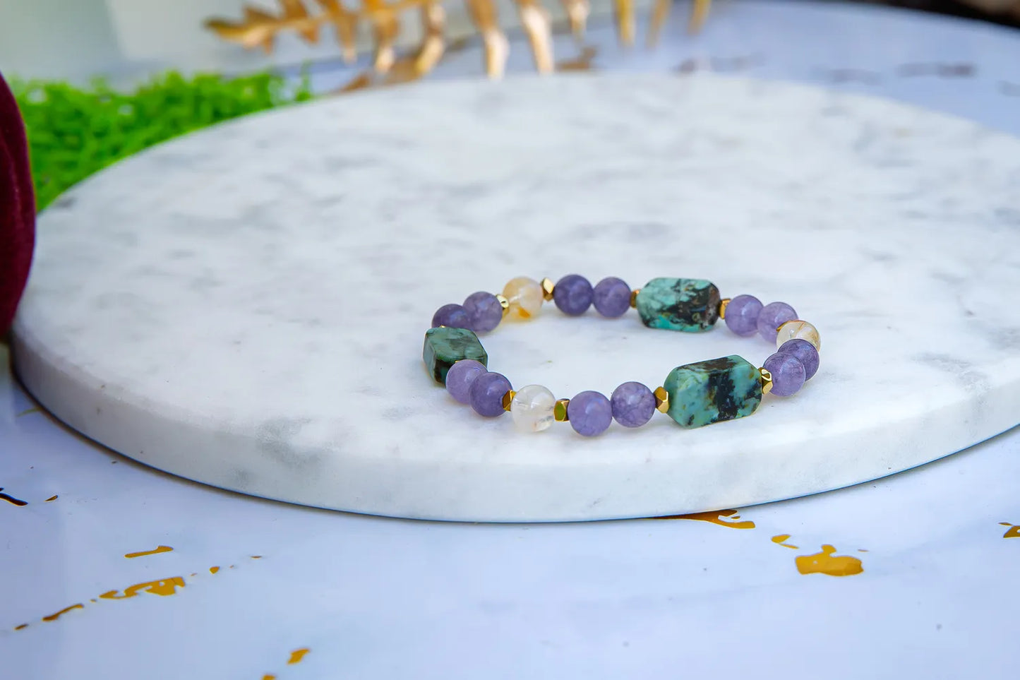 Bransoletka 'DROGA DUSZY' z turkusem afrykańskim, ametystem i cytrynem, ułożona na białym marmurowym tle. Biżuteria ręcznie robiona, z widocznymi kolorowymi kamieniami.