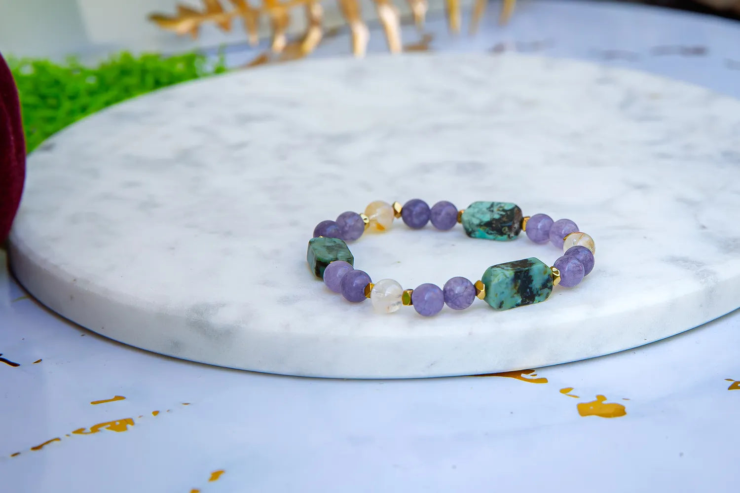 Bransoletka 'DROGA DUSZY' z turkusem afrykańskim, ametystem i cytrynem, ułożona na białym marmurowym tle. Biżuteria ręcznie robiona, z widocznymi kolorowymi kamieniami.
