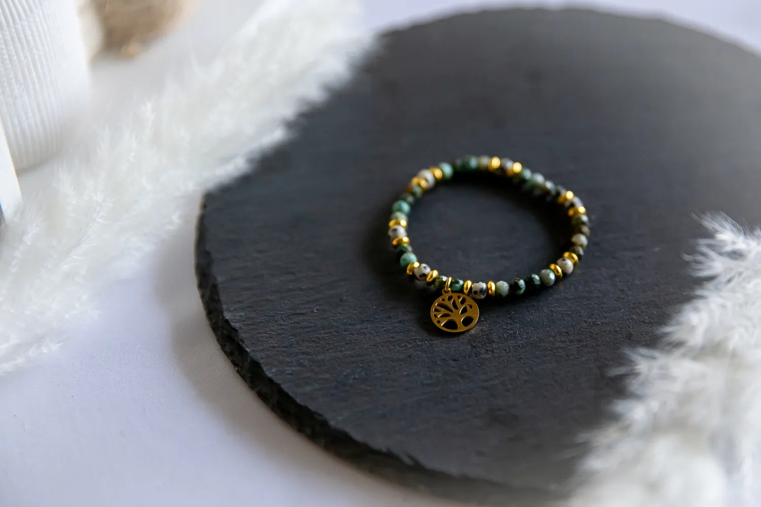 Gaj Madrosci Bransoletka Z Turkusem I Jaspisem - zloty medalion drzewko życia, turkusowo-zielone i żółte kamienie na czarnym tle.