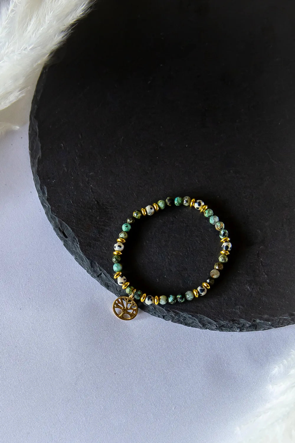 Gaj Madrosci Bransoletka Z Turkusem I Jaspisem z ozdobnym złotym drzewkiem życia, na tle czarnego łupka.