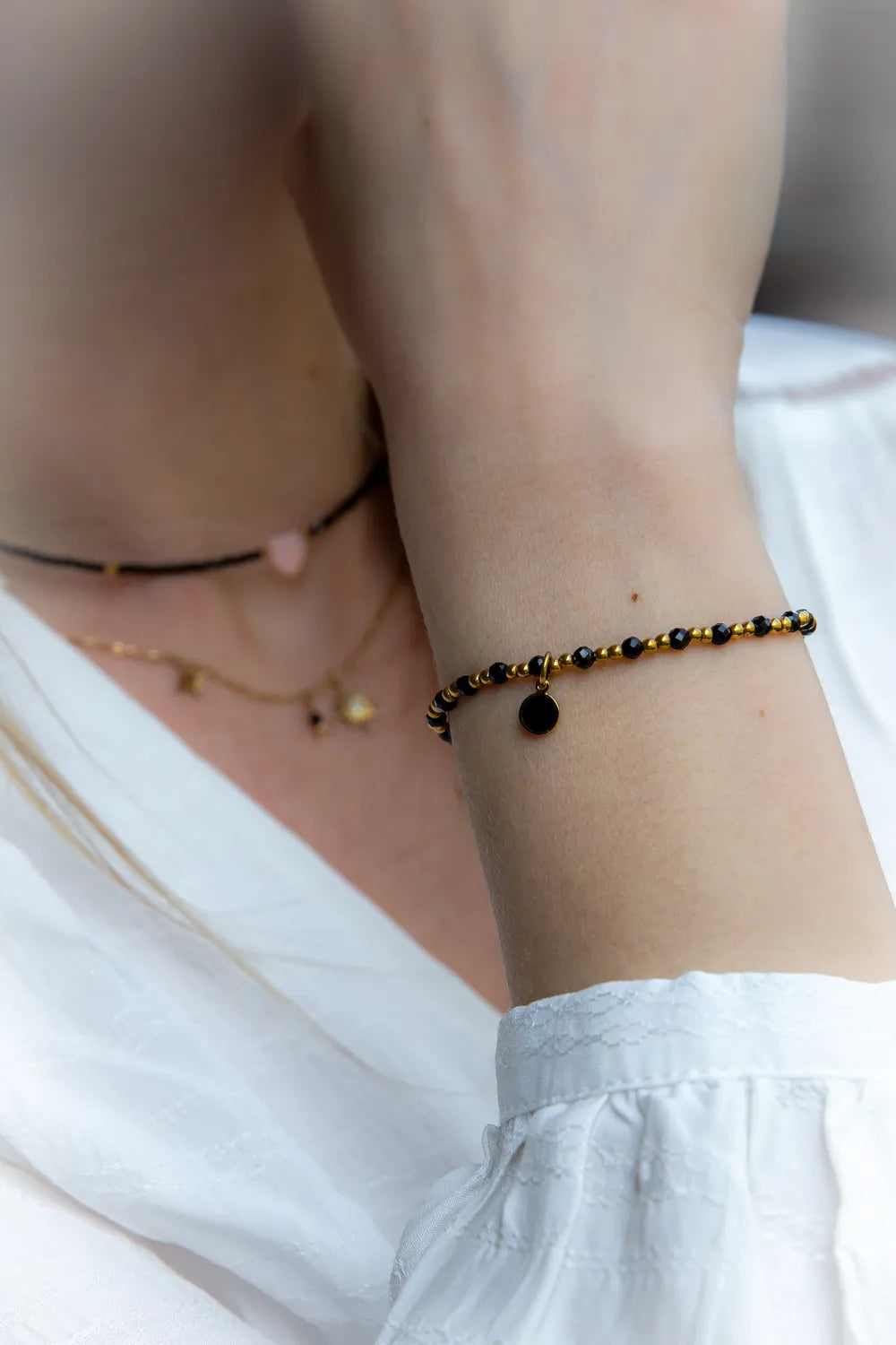 Klasyczna Elegancja Bransoletka Z Hematytu I Czarnego Turmalinu: czarne koraliki i hematyt na nadgarstku, z okrągłą przywieszką.