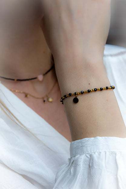 Klasyczna Elegancja Bransoletka Z Hematytu I Czarnego Turmalinu: czarne koraliki i hematyt na nadgarstku, z okrągłą przywieszką.