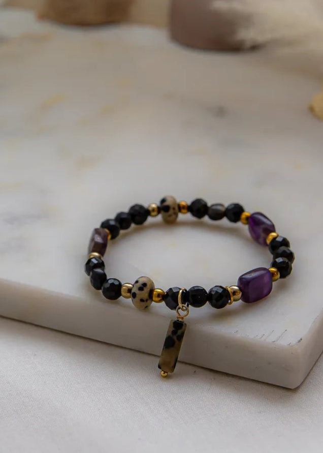 Królewska Ochrona Bransoletka Z Turmalinu I Ametystu z koralikami z turmalinu i ametystu na eleganckim marmurowym tle.