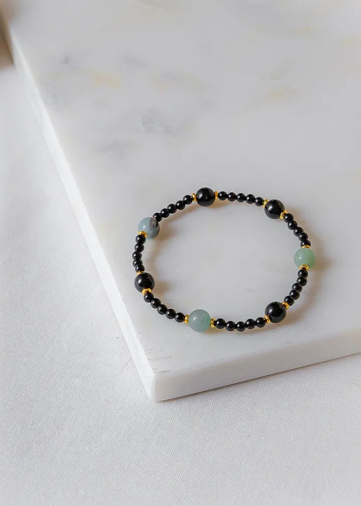 Lodowa Elegancja Bransoletka Agat Opal z czarnymi i zielonymi kamieniami, ułożona na białej powierzchni.