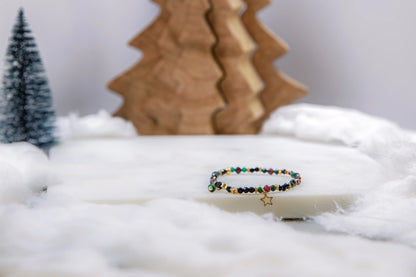 Bransoletka z motywem gwiazdy jako magiczny talizman-drogowskaz na prezent świąteczny. Biżuteria z kamieni naturalnych w otoczeniu choinek i sztucznego śniegu.