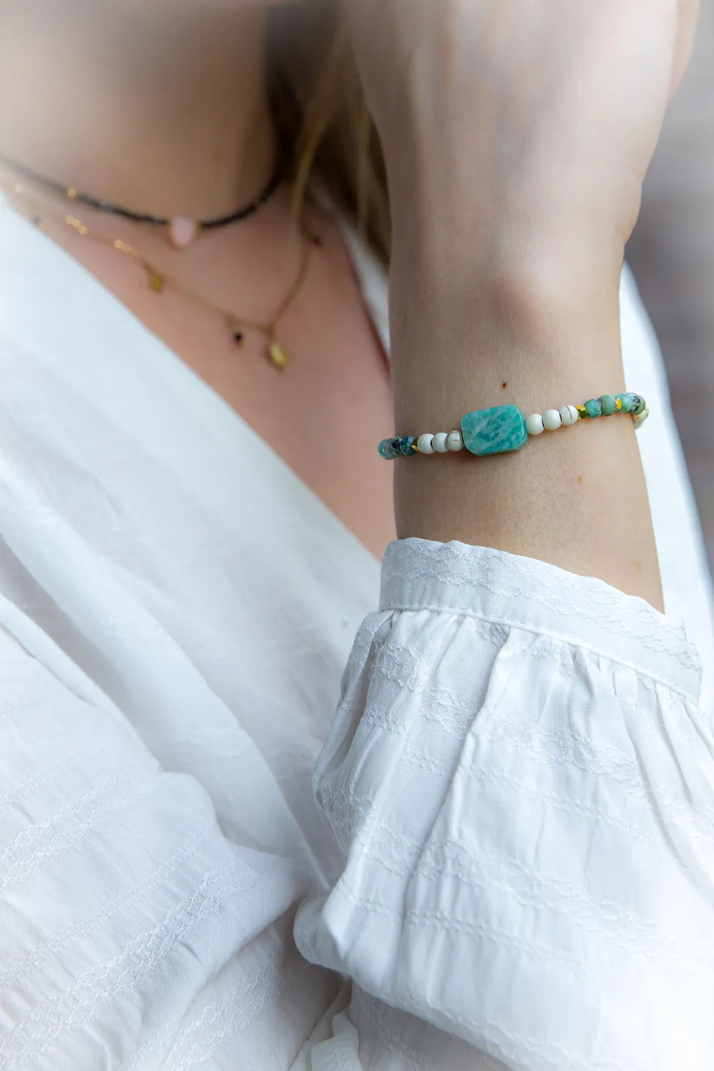 Morska Bryza Bransoletka Kamienie z centralnym, kwadratowym akwamarynem, otoczonym białymi i turkusowymi kamieniami.