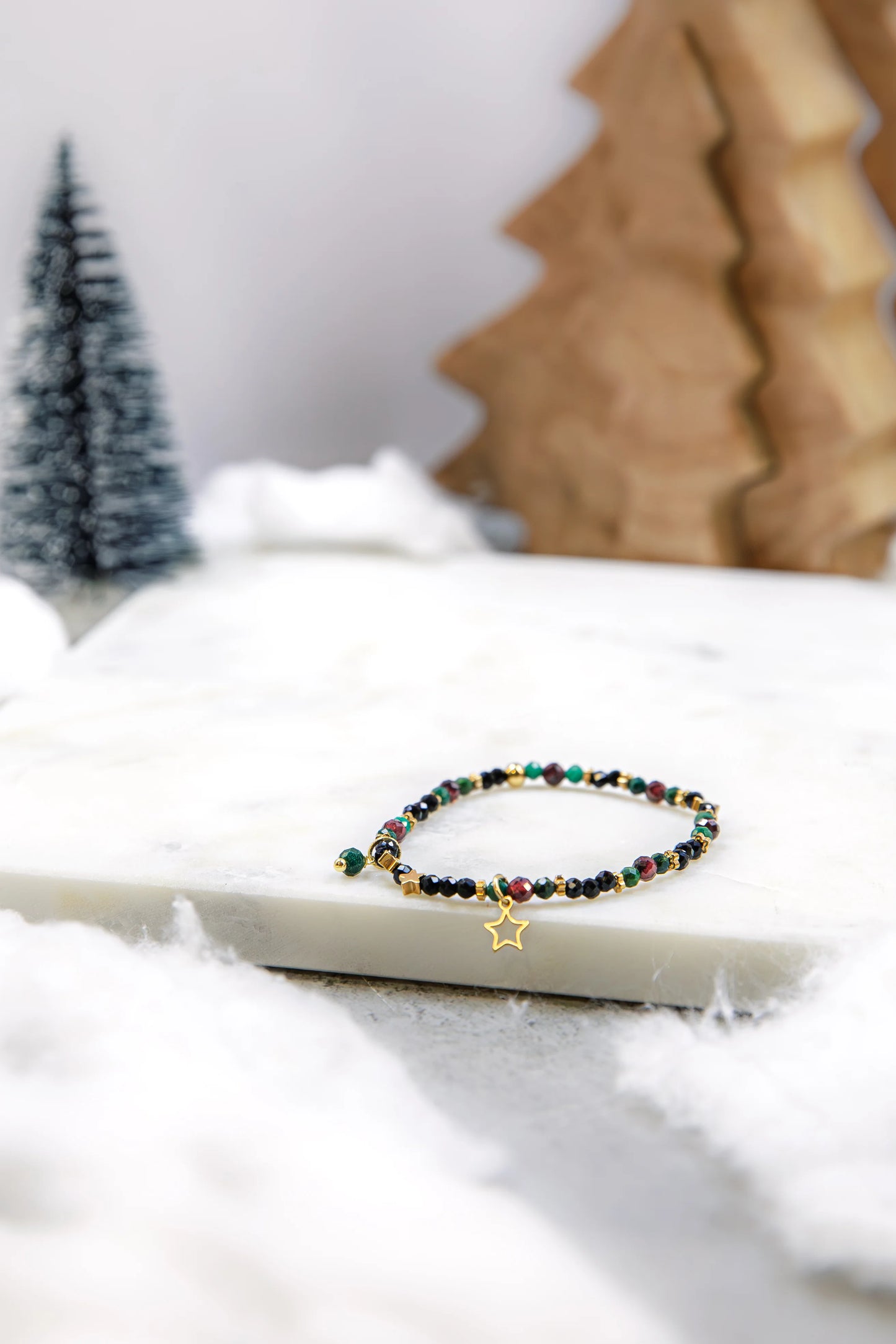 Ręcznie robiona bransoletka Pati Linka "Gwiazdy nad Nilem". Kompozycja z naturalnego szmaragdu Nilu, czerwonego granatu i czarnego spinelu ze złotą zawieszką gwiazdką w zimowej aranżacji.