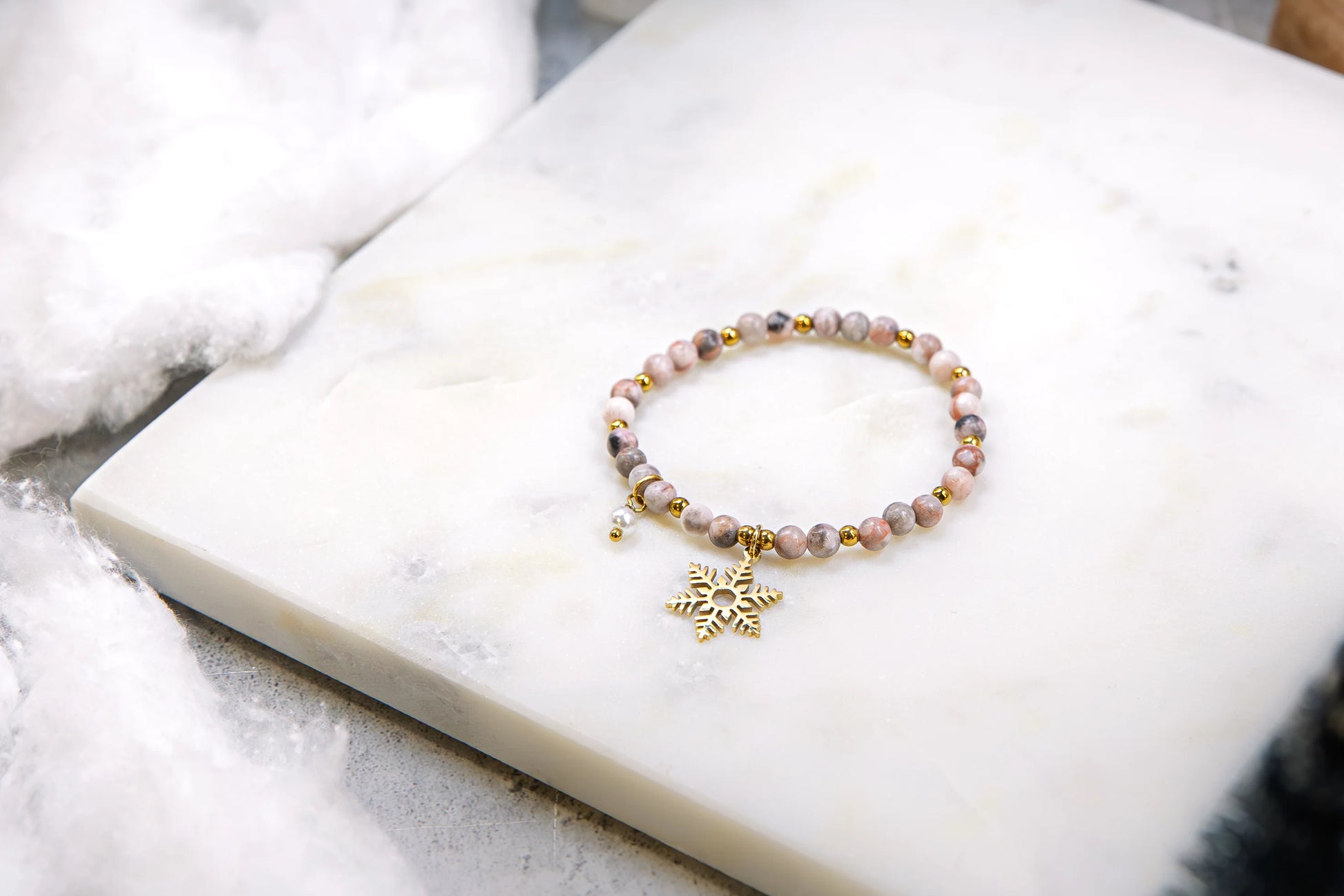 Widok z góry na elastyczną bransoletkę z kamieni naturalnych ze złotymi akcentami. Biżuteria celebrująca zimową unikalność i delikatność.