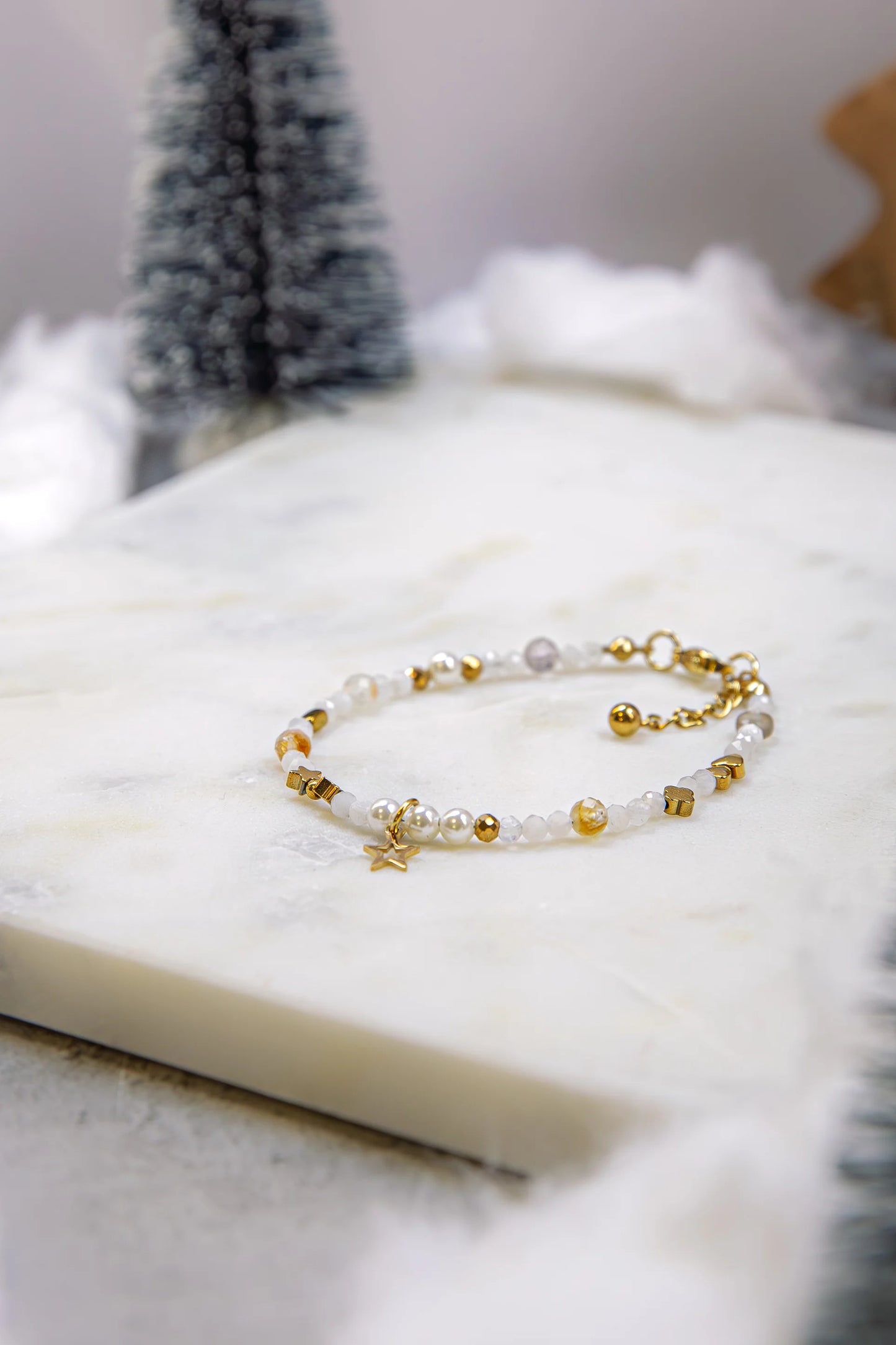 Widok z góry na elastyczną bransoletkę na gumce jubilerskiej. Widoczna harmonijna kompozycja różnorodnych kamieni naturalnych: cytrynu, jadeitu i kamienia słonecznego.