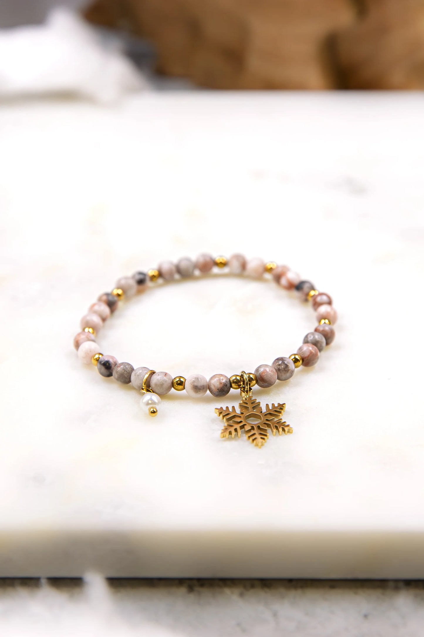 Naturalne kamienie rodonitu w odcieniach przygaszonego różu przeplatane złotym hematytem. Tekstura koralików w ręcznie robionej biżuterii.