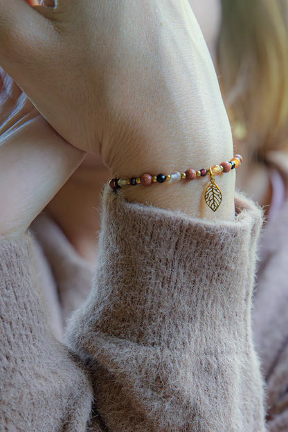 SERCE JESIENI - BRANSOLETKA Z KARNEOLU, GRANATU I CYTRYNU. Bransoletka z kolorowymi kamieniami i złotym liściem na tle delikatnej, beżowej bluzy.