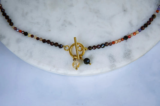 SERCE KRÓLOWEJ - NASZYJNIK Z GRANATU, SPINELU I CYTRYNU, elegancki naszyjnik z kolorowymi kamieniami, ułożony na białym tle z dekoracją w tle.