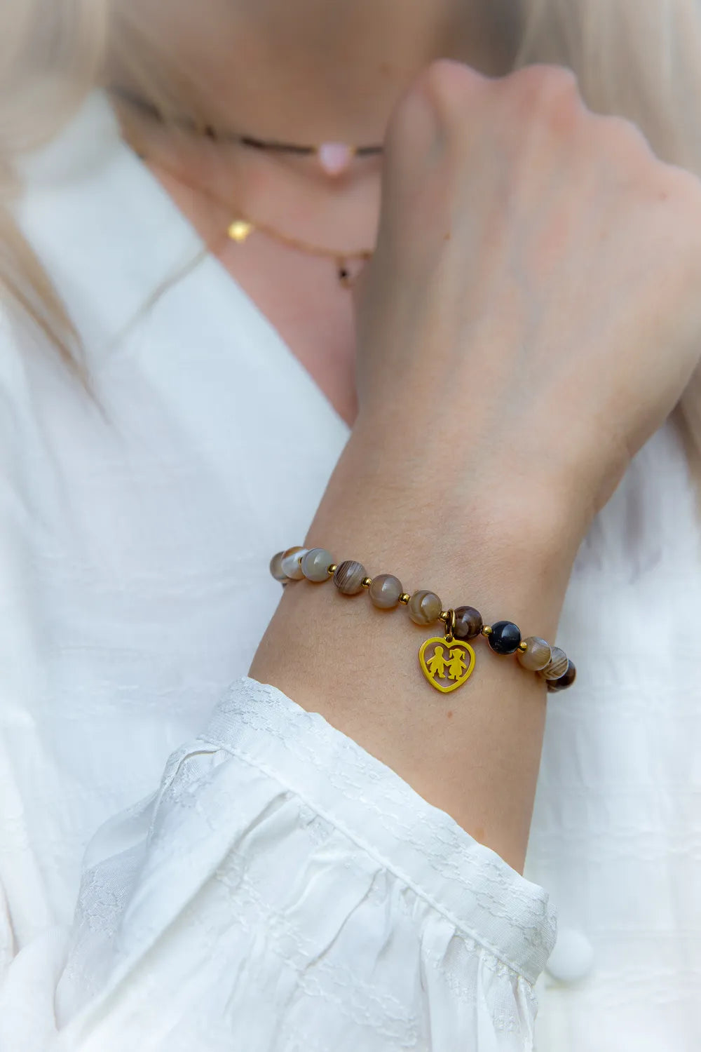 Bransoletka Serce Rodziny Agat, wielokolorowe kamienie agatu, złota zawieszka w kształcie serca z dwiema figurkami dzieci.