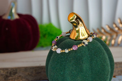 SŁODKI IMPULS - BRANSOLETKA Z JASPISU DALMATYŃSKIEGO I JADEITU. Bransoletka z kolorowymi kamieniami na zielonym tle w kształcie dyni, z czerwoną dynią i złotym dekoracyjnym elementem w tle.