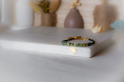 Szczęśliwa Koniczynka Bransoletka Z Turmalinu Czarnego I Turkusu Afrykańskiego Biustonosz z zawieszką koniczynką na tle dekoracji.