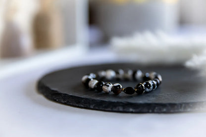 Tao Równowagi Bransoletka Agat Panda Hematyt - czarno-białe kamienie agatu i czarny hematyt na ciemnej płycie, z rozmytym jasnym tłem.