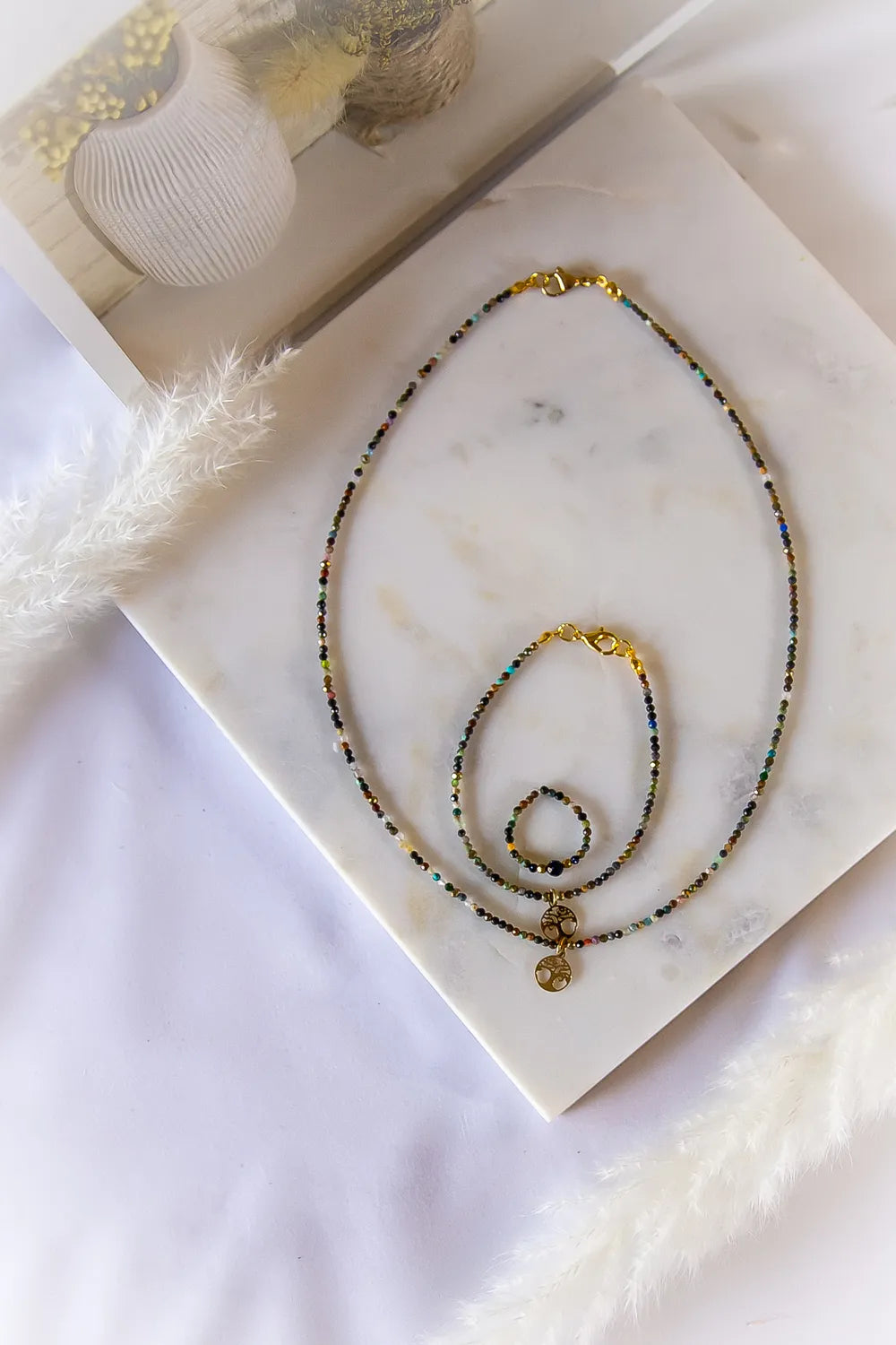 Zestaw biżuterii "Tęczowa Harmonia Turmalin Drzewko Szczęścia" - naszyjnik, bransoletka i pierścionek z turmalinów oraz złotymi zawieszkami drzewka życia.