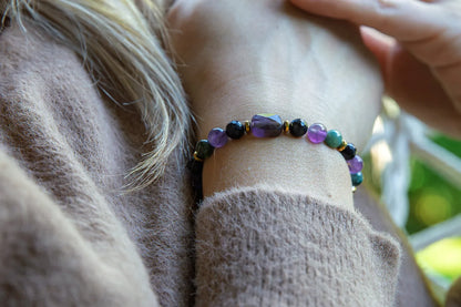 WRZOSOWA NOC - BRANSOLETKA Z AMETYSTU I AGATU INDYJSKIEGO na nadgarstku kobiety. Biżuteria ręcznie robiona z kolorowymi kamieniami, tło z naturalnym światłem i delikatnym ubraniem.