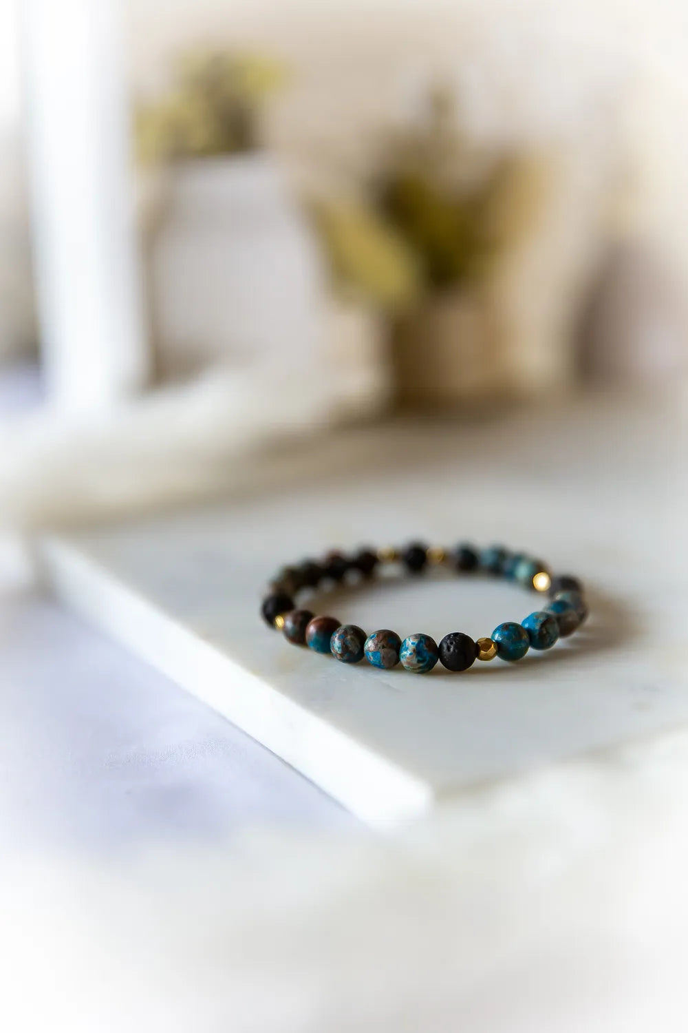 Wulkaniczna Moc Bransoletka Z Turkusem I Lawą z turkusowymi i lawowymi kamieniami, ułożona na białym marmurze.