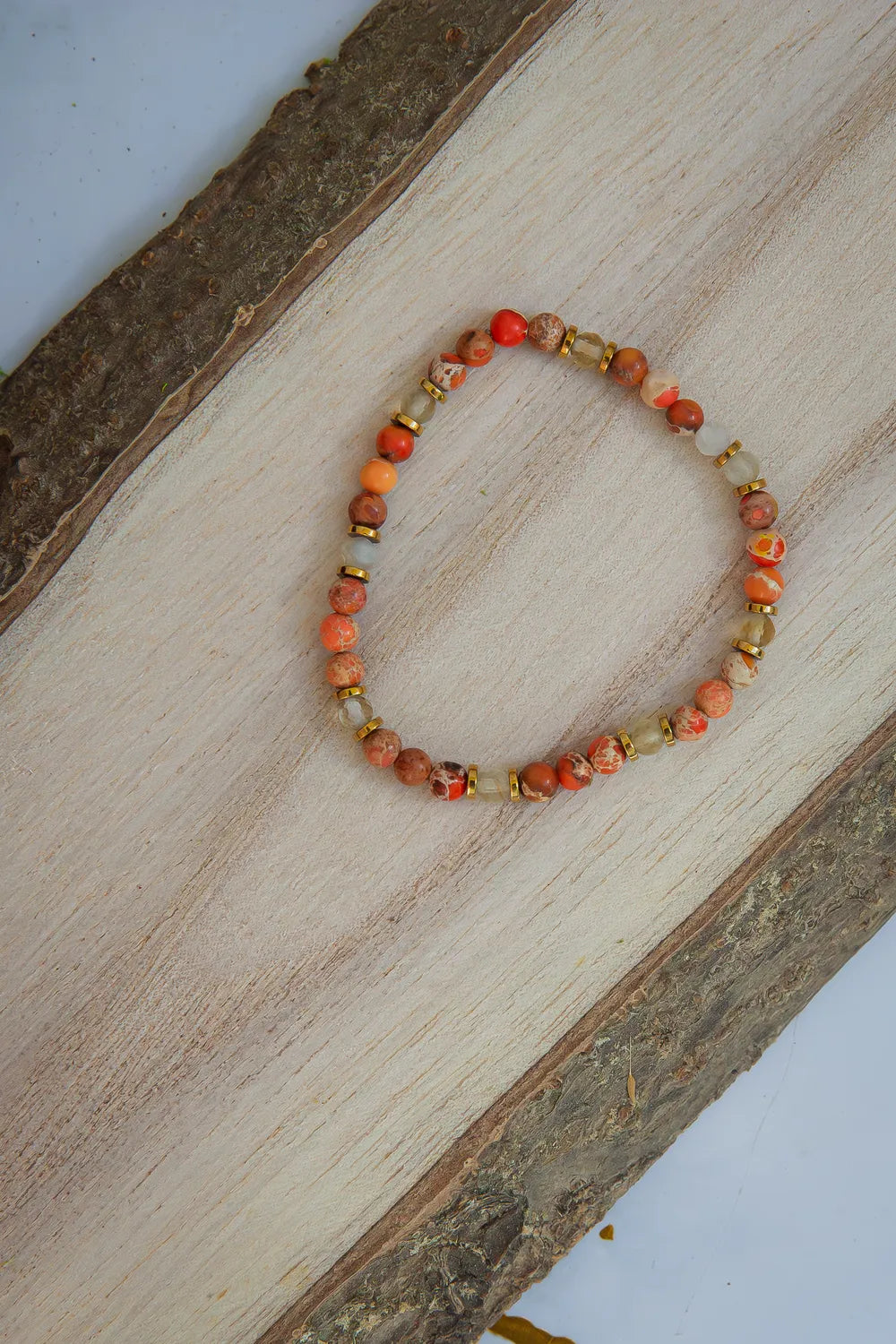 ZŁOTA GODZINA - BRANSOLETKA Z JASPISU I CYTRYNU, bransoletka z kolorowymi kamieniami jaspisu i cytrynu, ułożona na drewnianym tle.
