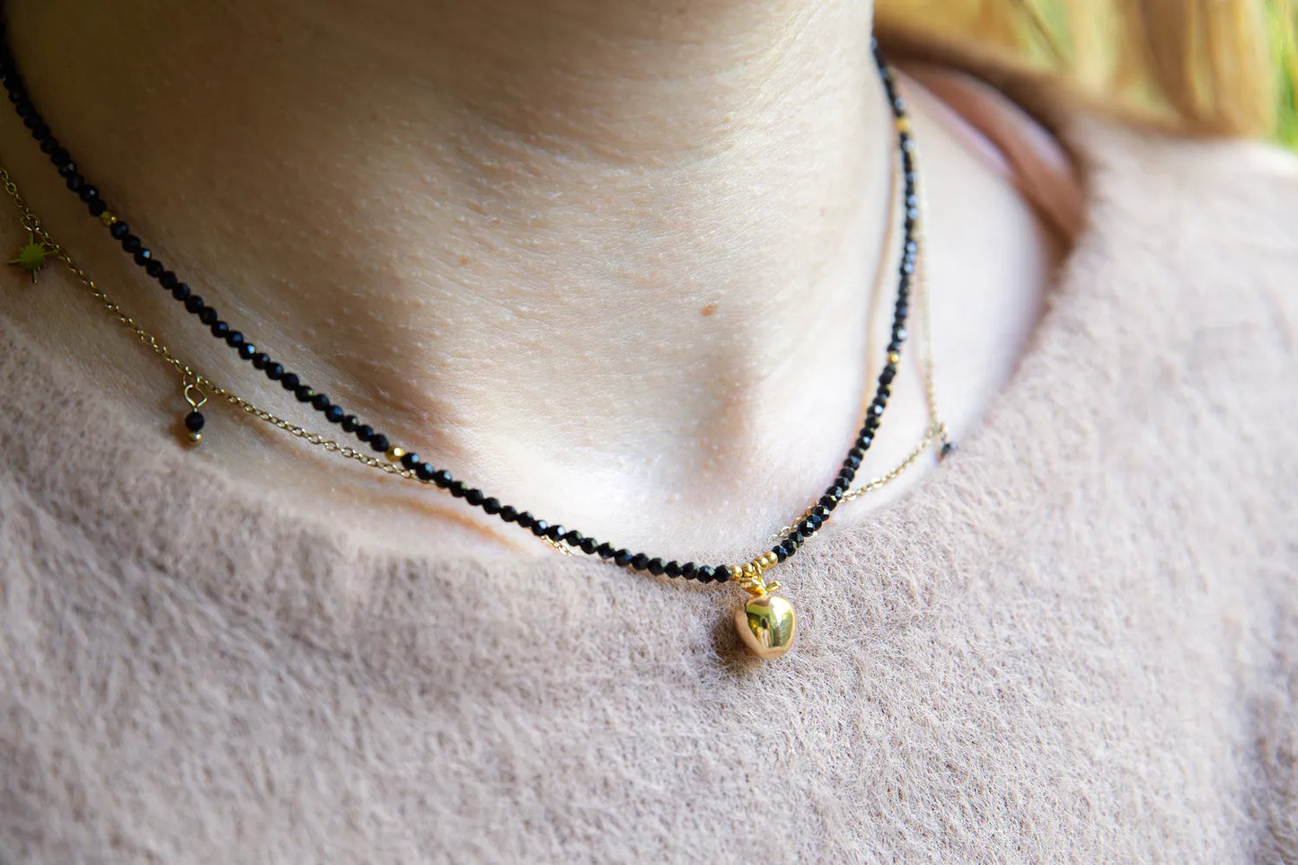 ZŁOTE JABŁKO - NASZYJNIK Z CZARNEGO TURMALINU. Dwuwarstwowy naszyjnik z czarnymi koralikami turmalinu i złotym jabłkiem na delikatnym tle skóry.